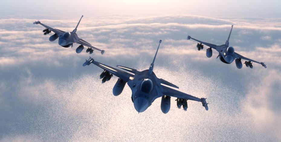 three military airplanes flying at sunset